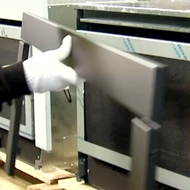 Gloved hands fitting a panel on the factory line